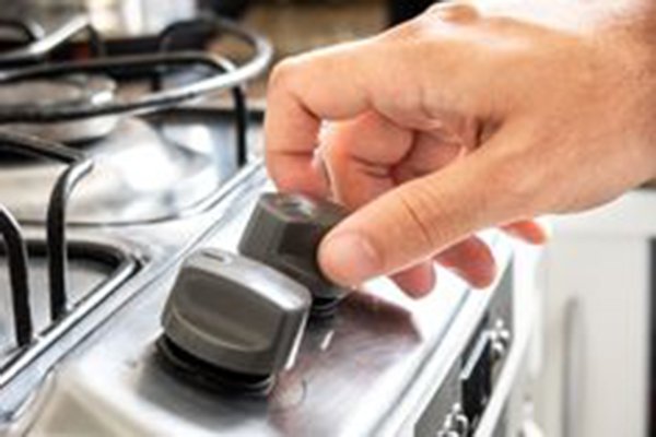 Gas control knobs of a domestic stoveHand of a man pressing and turning gas control knobs of a domestic stove to lighting the stove